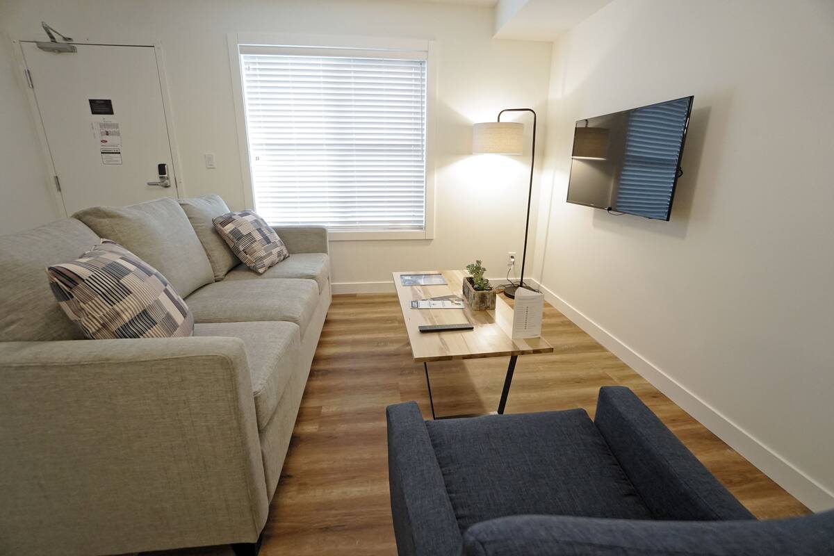 A living room with a sofa, a coffee table, and a TV mounted on the wall.
