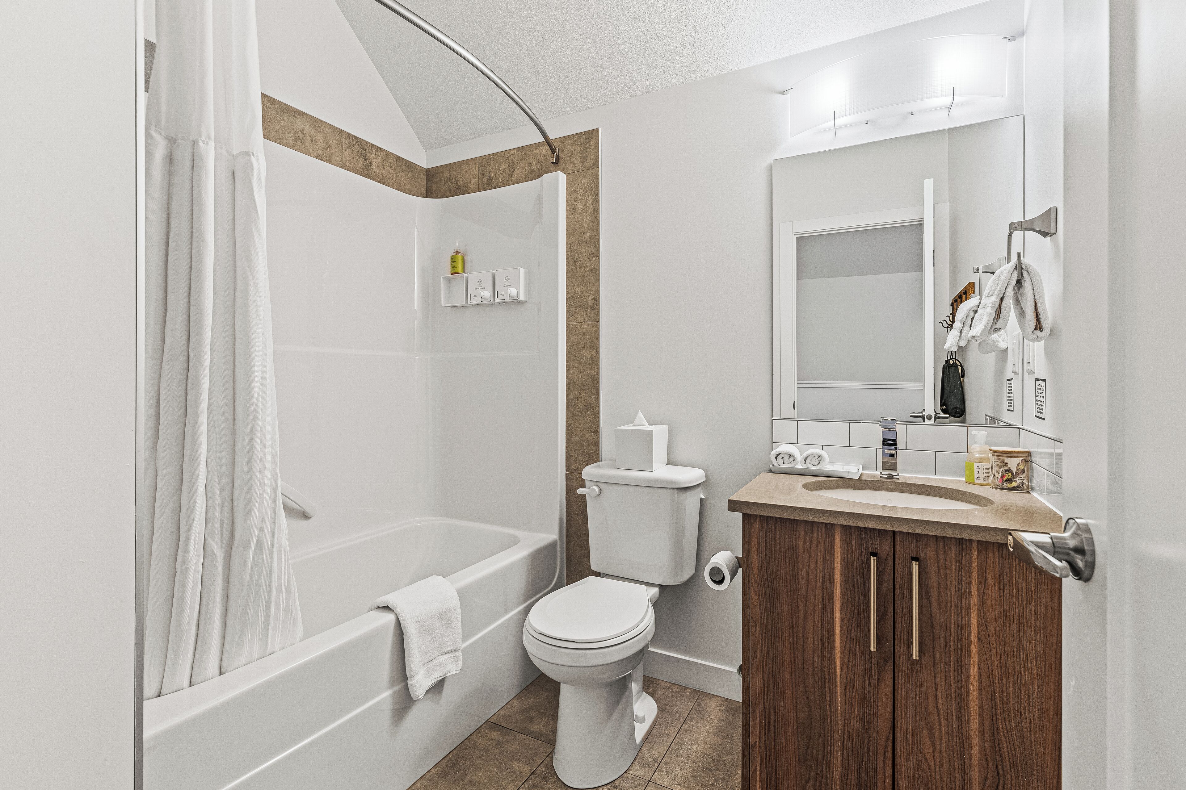 A modern bathroom with a bathtub, toilet, and vanity.
