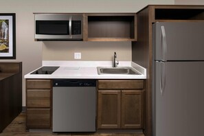 Una cocina moderna con microondas integrado, pileta de acero inoxidable y lavavajillas.