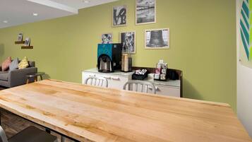 A modern kitchen with a wooden table, white cabinets, and a coffee machine.