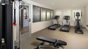 A gym with treadmills, a bench, and weightlifting equipment. - WoodSpring Suites Cherry Hill (Cherry Hill)