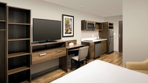 A modern hotel room with a large bed, a desk with a computer, a TV, a microwave, a refrigerator, and a small kitchenette. - WoodSpring Suites South Plainfield (South Plainfield)