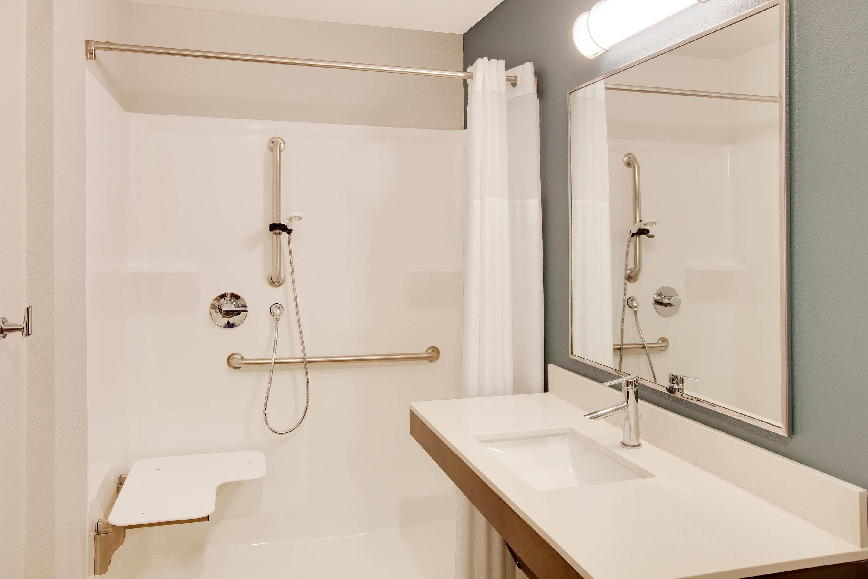 A modern bathroom with a walk-in shower, a vanity with a mirror, and a toilet.