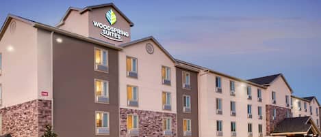 Un hotel de varios pisos con un letrero llamativo de WoodSpring Suites.