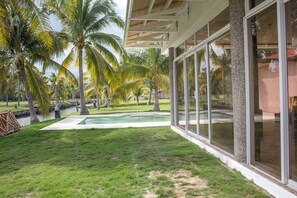 A pool area with a clear view of the surrounding palm trees and a covered seating area with large windows.