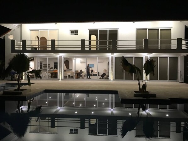 A modern multi-story hotel with a spacious lobby, a pool area, and a well-lit exterior.