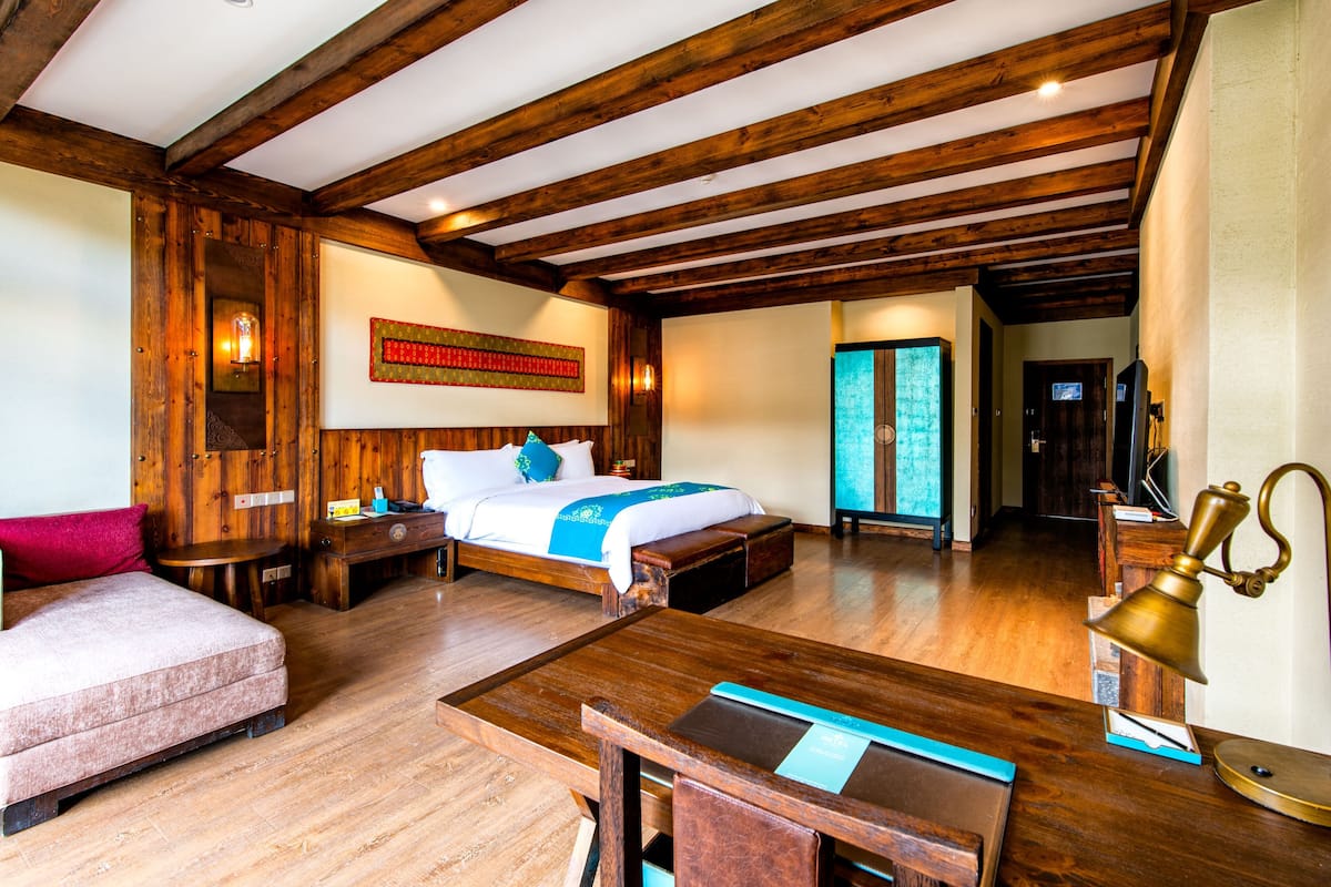 Ein Schlafzimmer mit Holzboden, einem Bett, einem Schreibtisch und einem Stuhl.