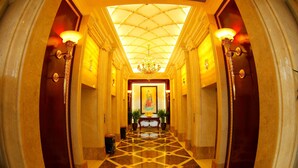 A grand hallway with a geometric patterned floor, a chandelier, and a framed painting on the wall. - Enrichee Gloria Plaza Hotel Qingdao (Qingdao)