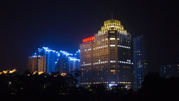 A high-rise building with illuminated windows and a distinctive top section. - Enrichee Gloria Plaza Hotel Qingdao (Qingdao)
