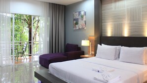 Habitación de hotel con una cama grande, una silla, un escritorio y vistas a zonas verdes por la ventana.