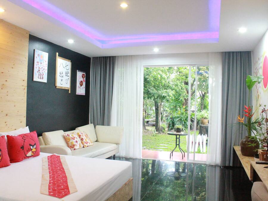 Habitación de hotel con cama, sofá, una mesita y vistas al jardín.