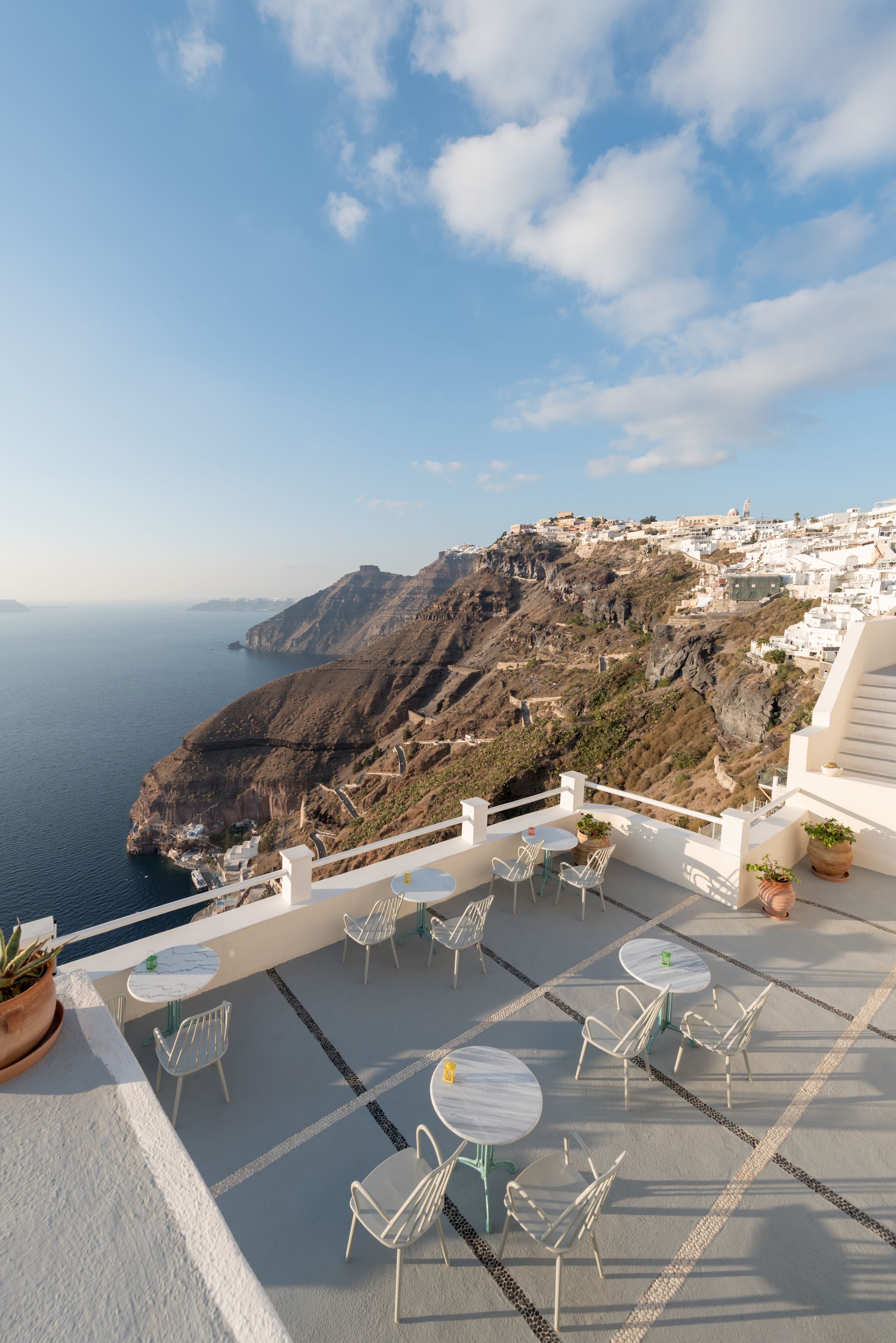 A terrace with outdoor seating and a view of a coastal town.
