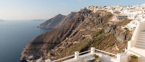 A terrace with outdoor seating and a view of a coastal town.