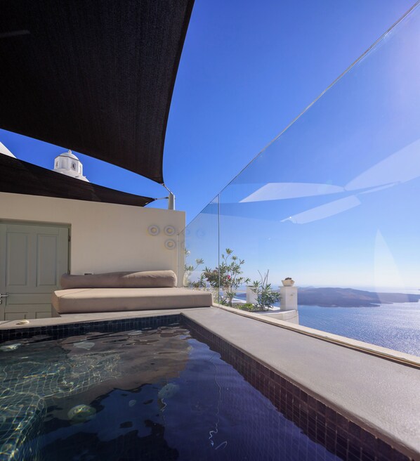 A pool with clear blue water, a white building with a dome, and a view of the sea.
