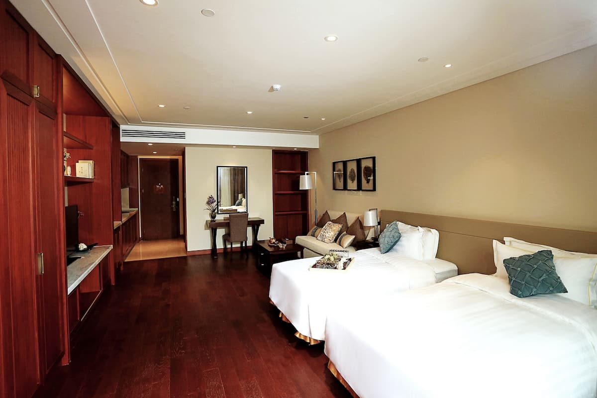 A hotel room with two beds, a desk, and a wardrobe.