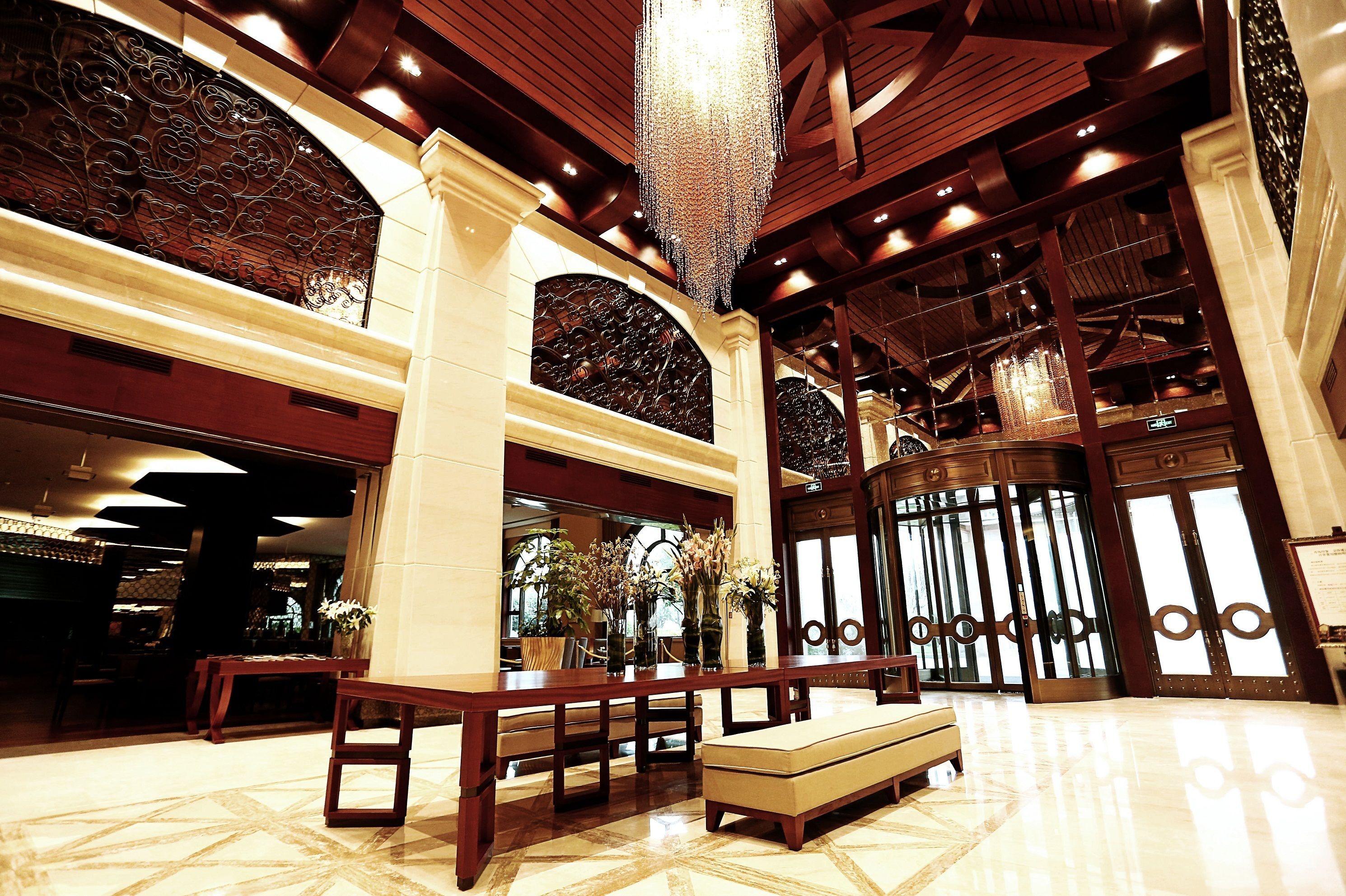 A spacious lobby with a high ceiling, ornate ironwork, and a large chandelier.