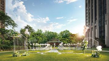An outdoor wedding venue with a gazebo, white chairs, and floral decorations.