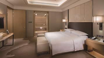 A modern hotel room with a large bed, bedside tables, a desk, and a shower area.