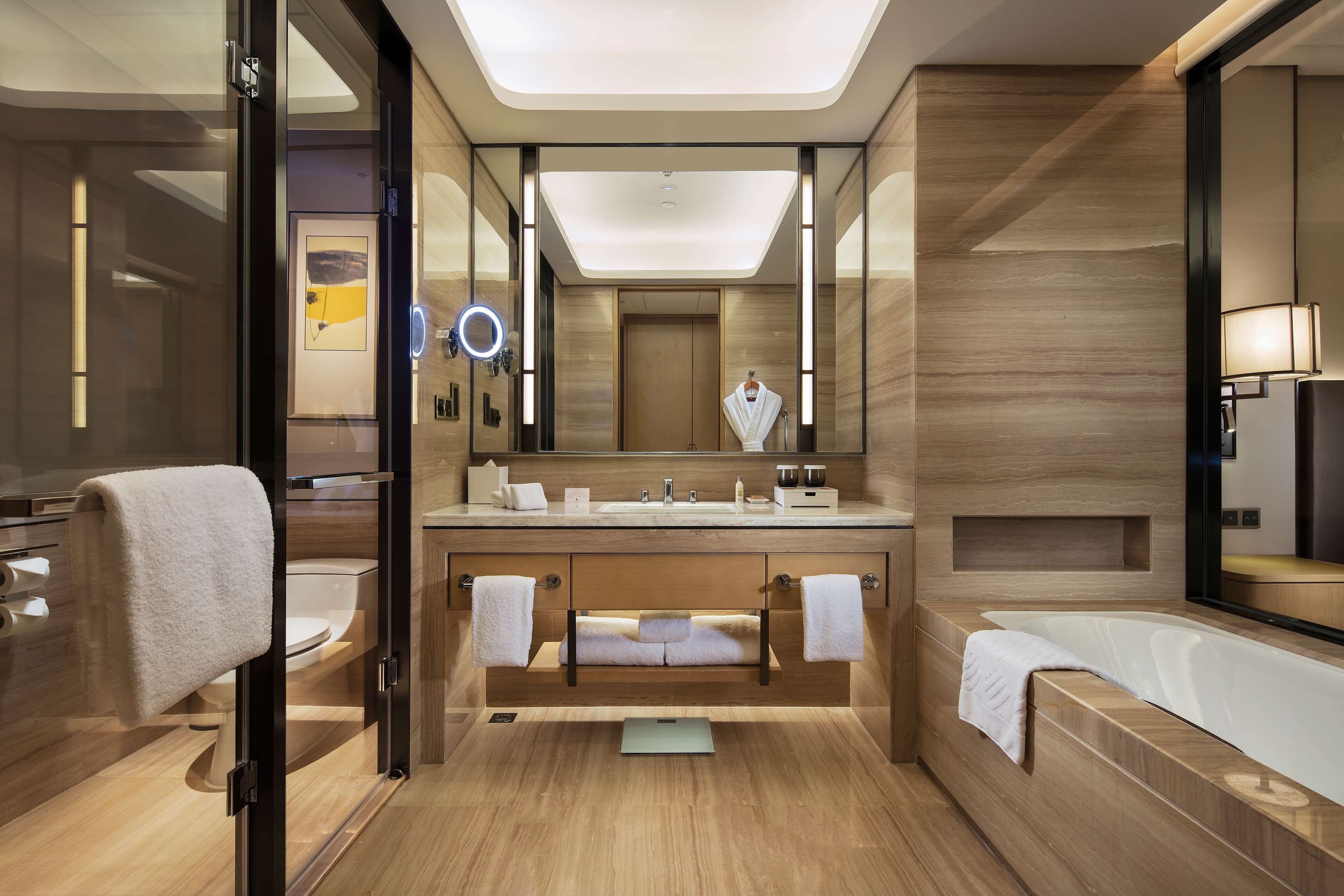 Une salle de bain moderne dotée d’une douche à parois de verre, d’un grand miroir, d’une baignoire et d’un meuble-lavabo avec un évier et un porte-serviettes.
