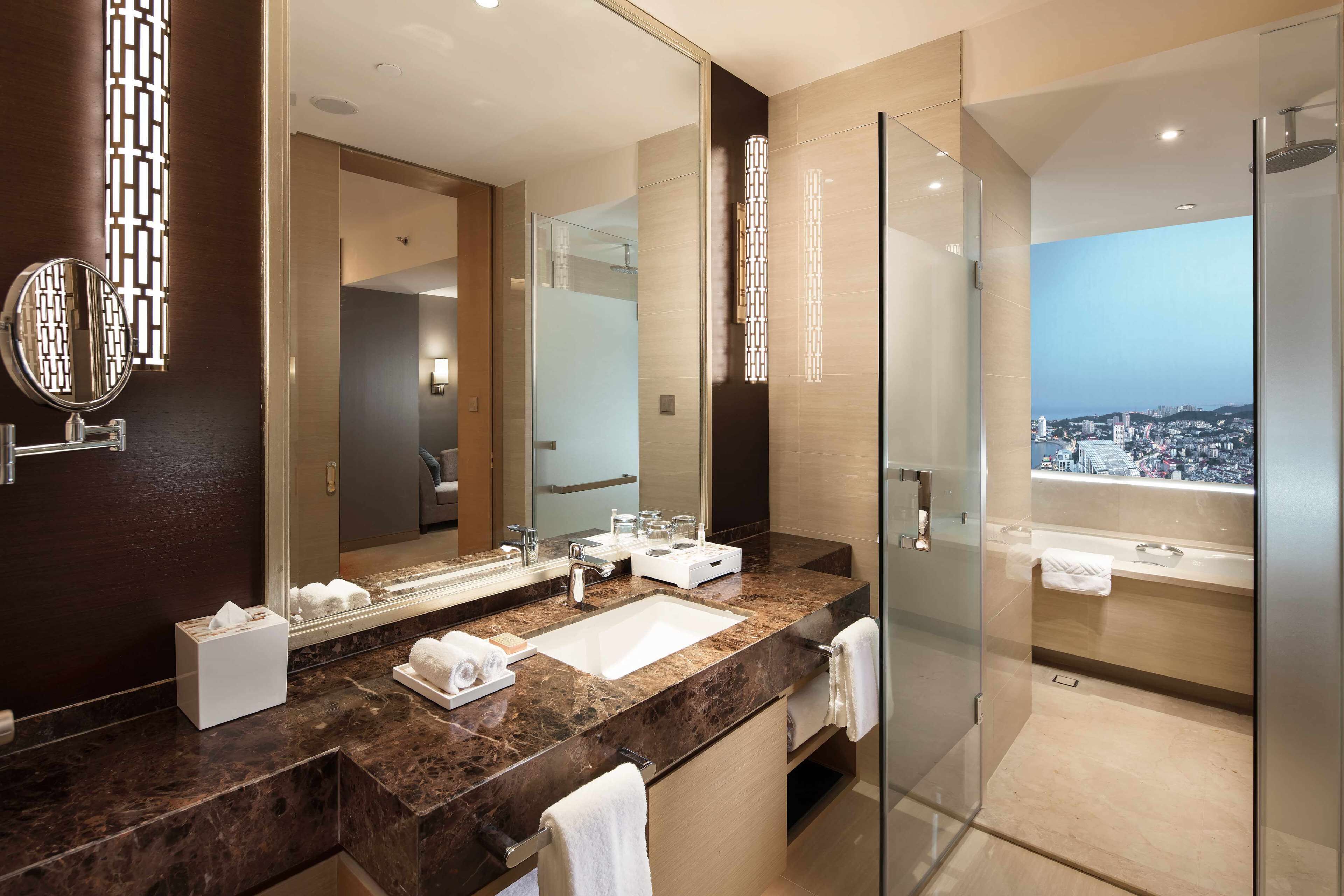 Un baño moderno con un espejo grande, un lavabo de mármol y una ducha con cerramiento de vidrio.