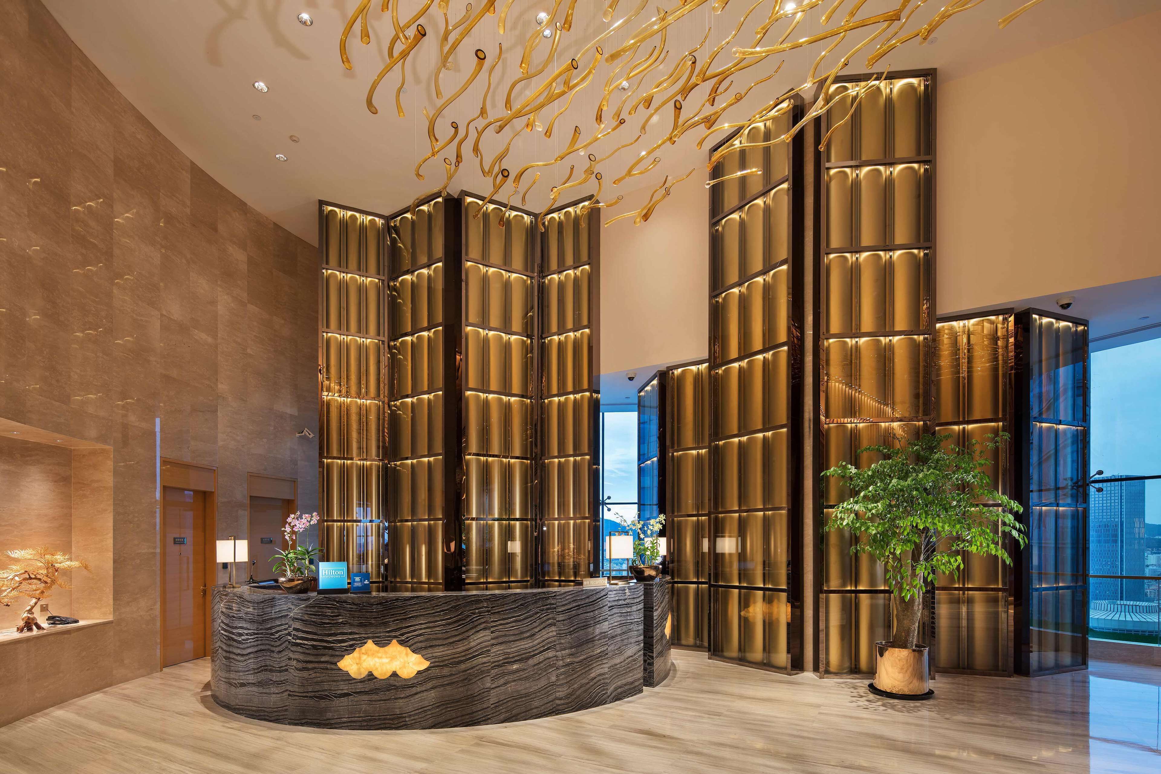 A modern reception area with a curved reception desk, vertical light panels, and a large window offering a view of the cityscape.