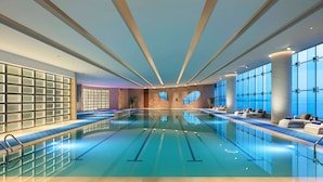 Una piscina interior con carriles delimitados, grandes ventanales y zonas de descanso a lo largo de los bordes.