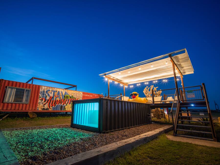 A container house with a mural, a small stage, and a yellow duck statue.
