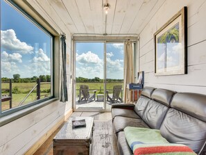 A cozy room with a leather sofa, a small table, and a window overlooking a grassy field.