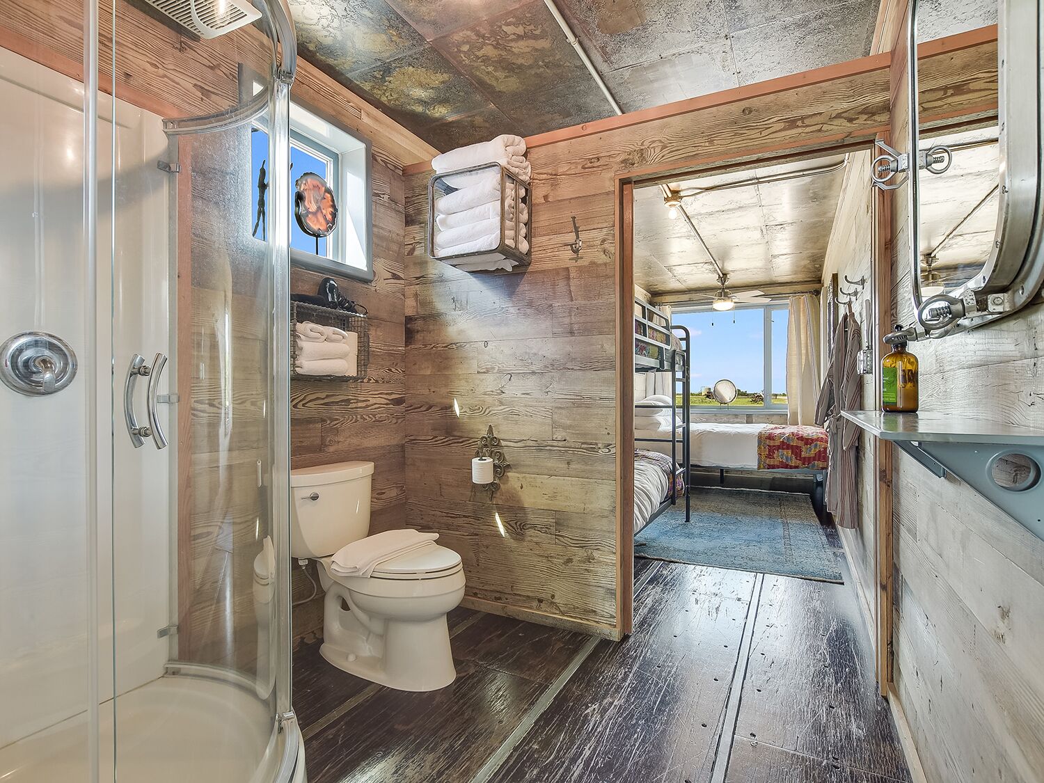 A compact bathroom with a shower, toilet, and a small window.