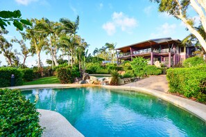 A modern building with a pool surrounded by lush greenery and palm trees.