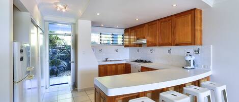 A modern kitchen with wooden cabinets, a white countertop, and a built-in island with bar stools.