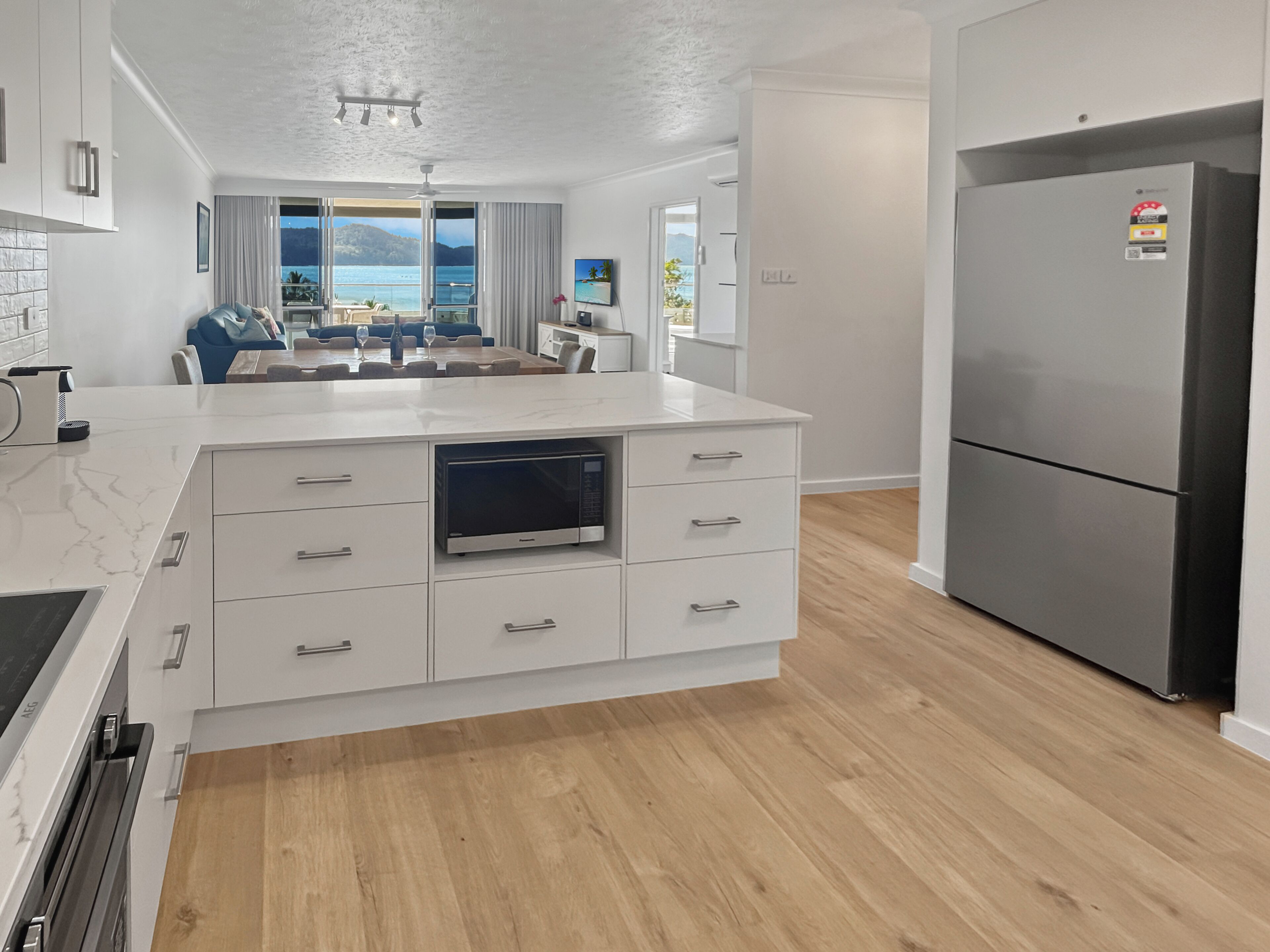 Eine moderne Küche mit Backofen, großem Kühlschrank und Essbereich mit Meerblick.