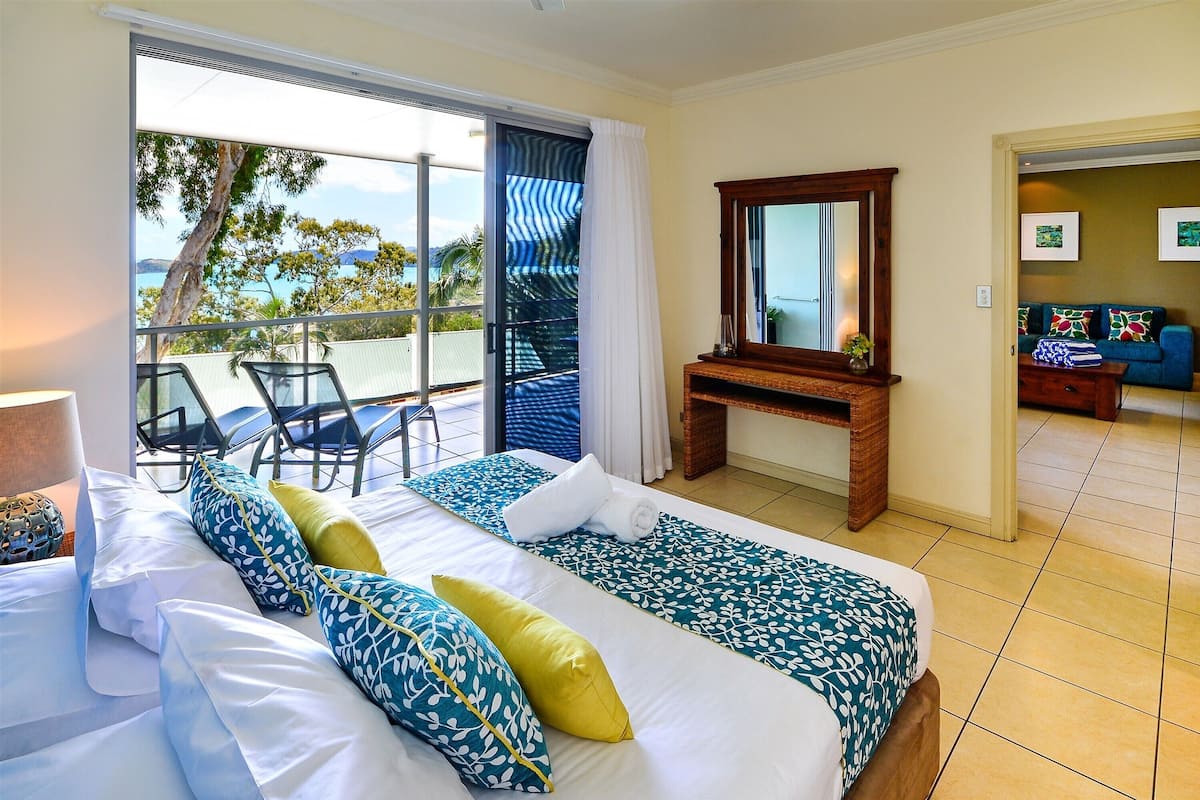 A hotel room with a bed, a desk, and a view of the ocean.