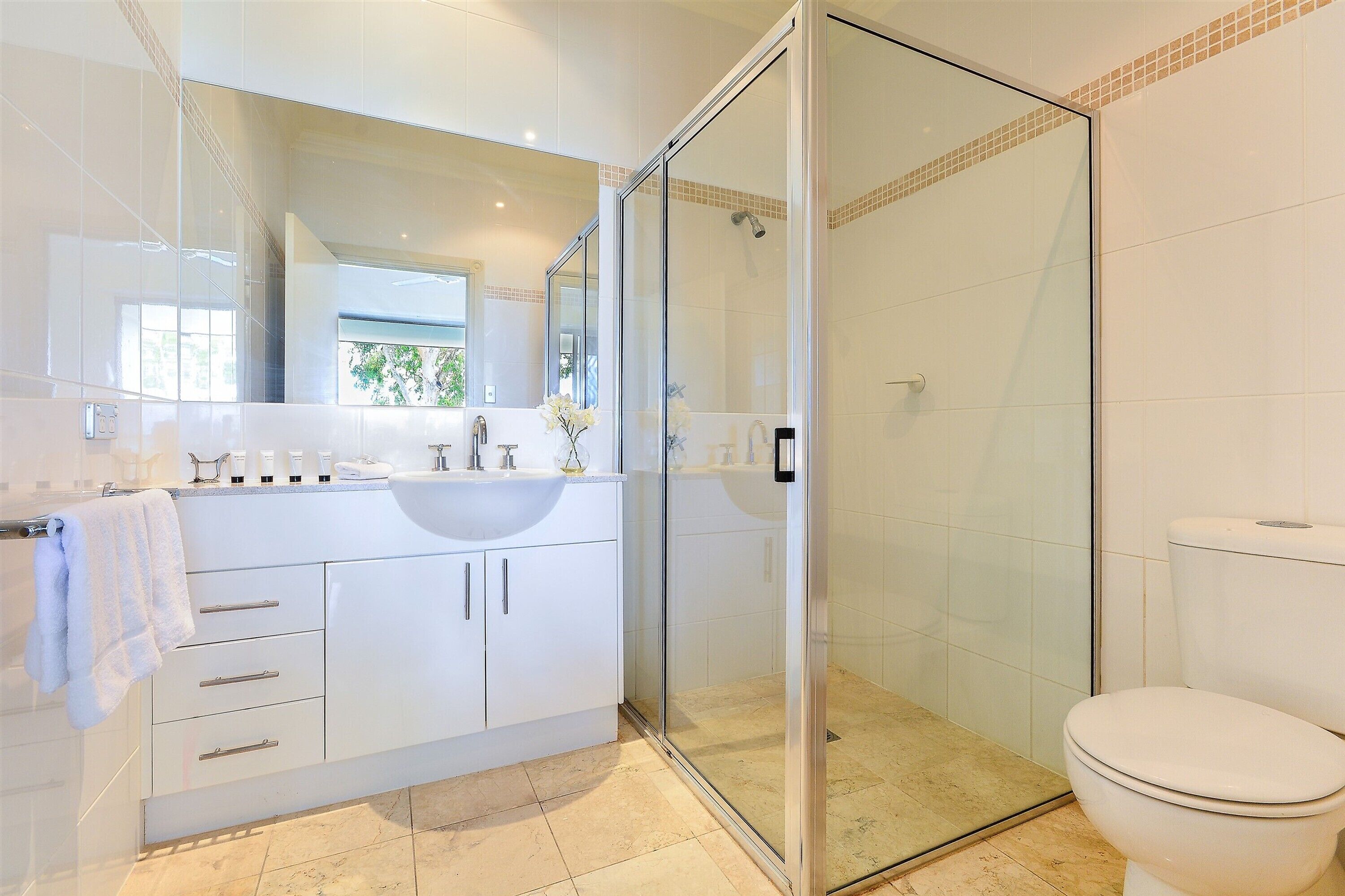 A modern bathroom with a glass-enclosed shower, a white sink, and a toilet.
