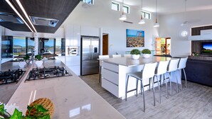 Une cuisine moderne dotée d’un îlot central, d’appareils électroménagers en acier inoxydable et d’une grande fenêtre donnant sur un paysage magnifique.