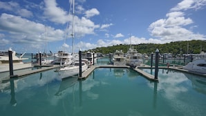 A marina with multiple boats docked at moorings, calm water, and a clear sky. - Heliconia Grove 9 (Whitsundays)