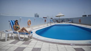 A rooftop pool with lounge chairs and umbrellas, surrounded by a high wall with lifebuoys. - Dock Masters Hotel Apartments (Dubai)