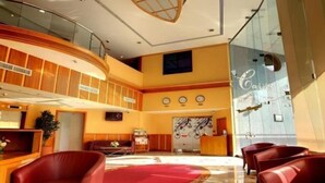 A lobby with a curved wooden wall, a reception desk, and red leather seating. - Dock Masters Hotel Apartments (Dubai)