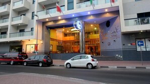 A modern hotel entrance with a prominent sign, multiple balconies, and flags. - Dock Masters Hotel Apartments (Dubai)