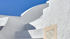 A white building with a series of steps leading to a door with a decorative window. - Nautilus (Santorini)
