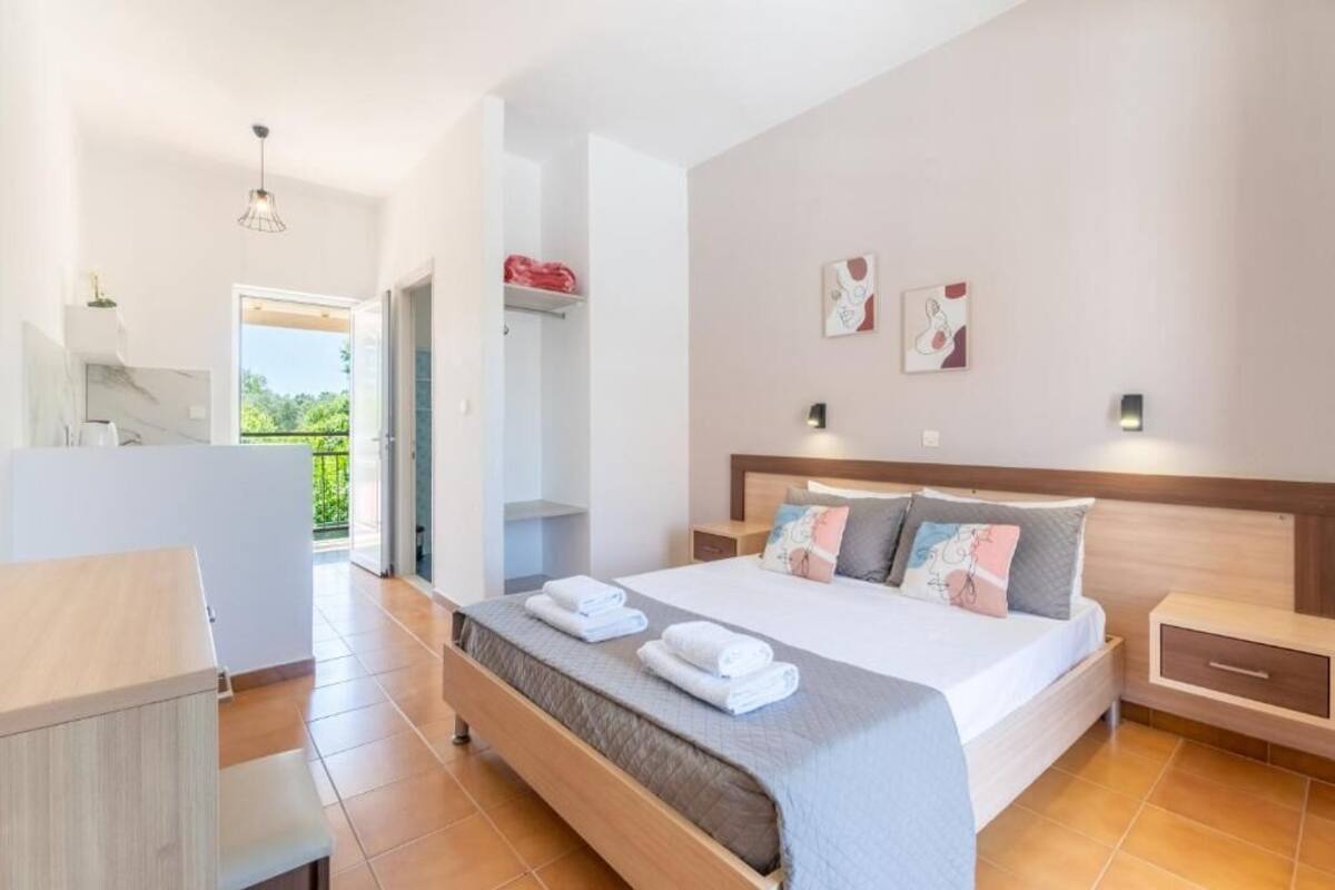 Ein modernes Schlafzimmer mit einem großen Bett, Nachttischen, einem Kleiderschrank und Blick ins Freie.