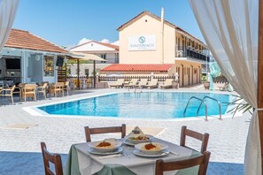 Una piscina al aire libre, sombrillas, sillones reclinables de piscina