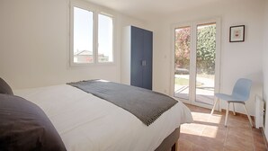 A bedroom with a bed, a blue wardrobe, a chair, and a sliding glass door leading to an outdoor area. - Impressive villa overlooking the hill (Joyeuse)