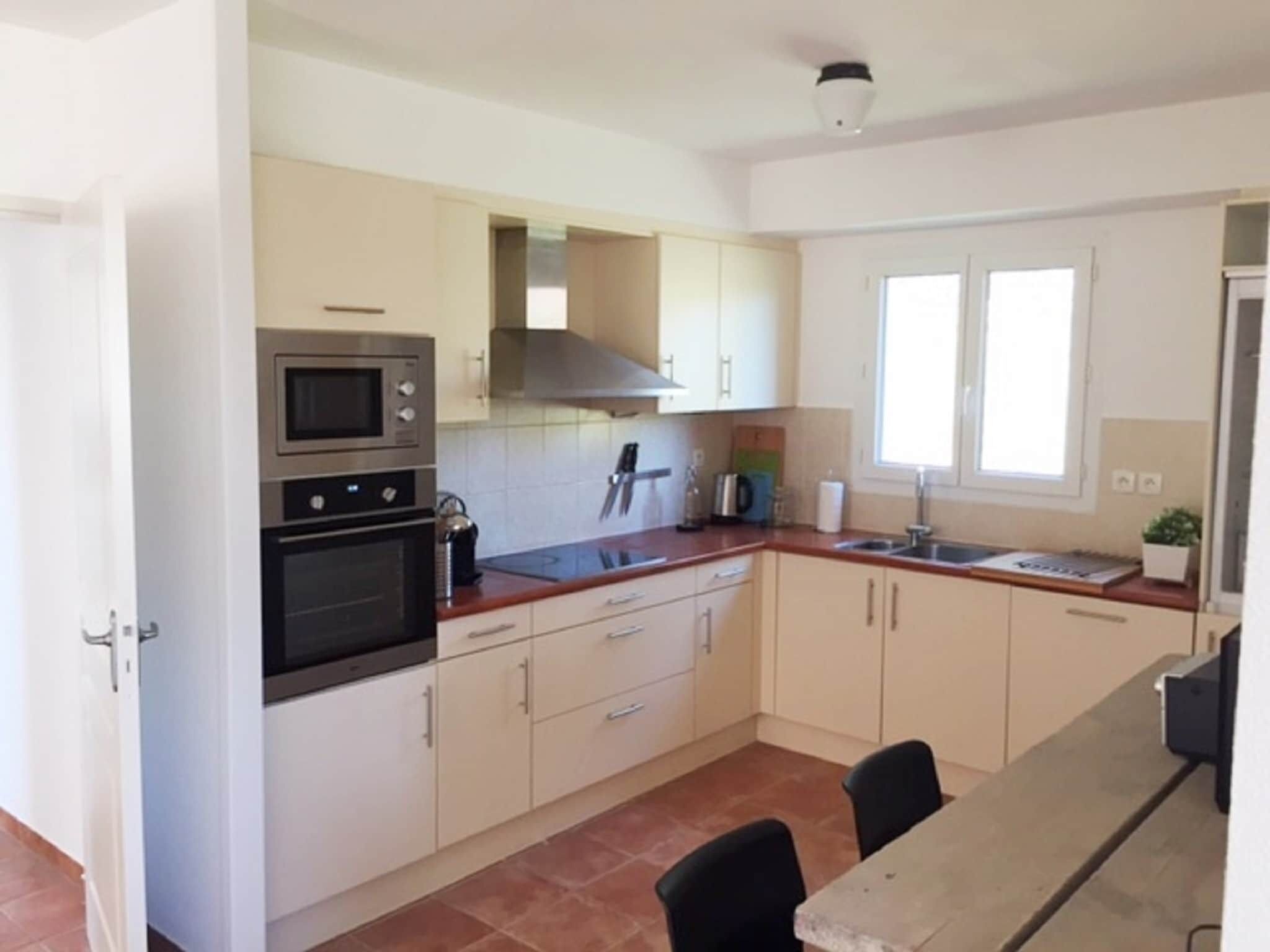 A kitchen with white cabinets, a double oven, a microwave, a stove, a sink, and a window.