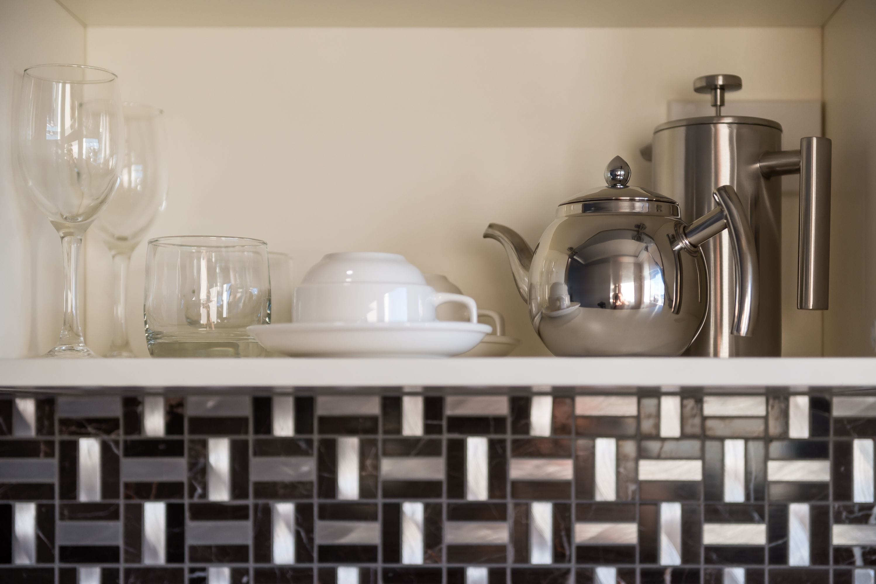 A kitchen counter with a coffee maker, a teapot, and two cups.