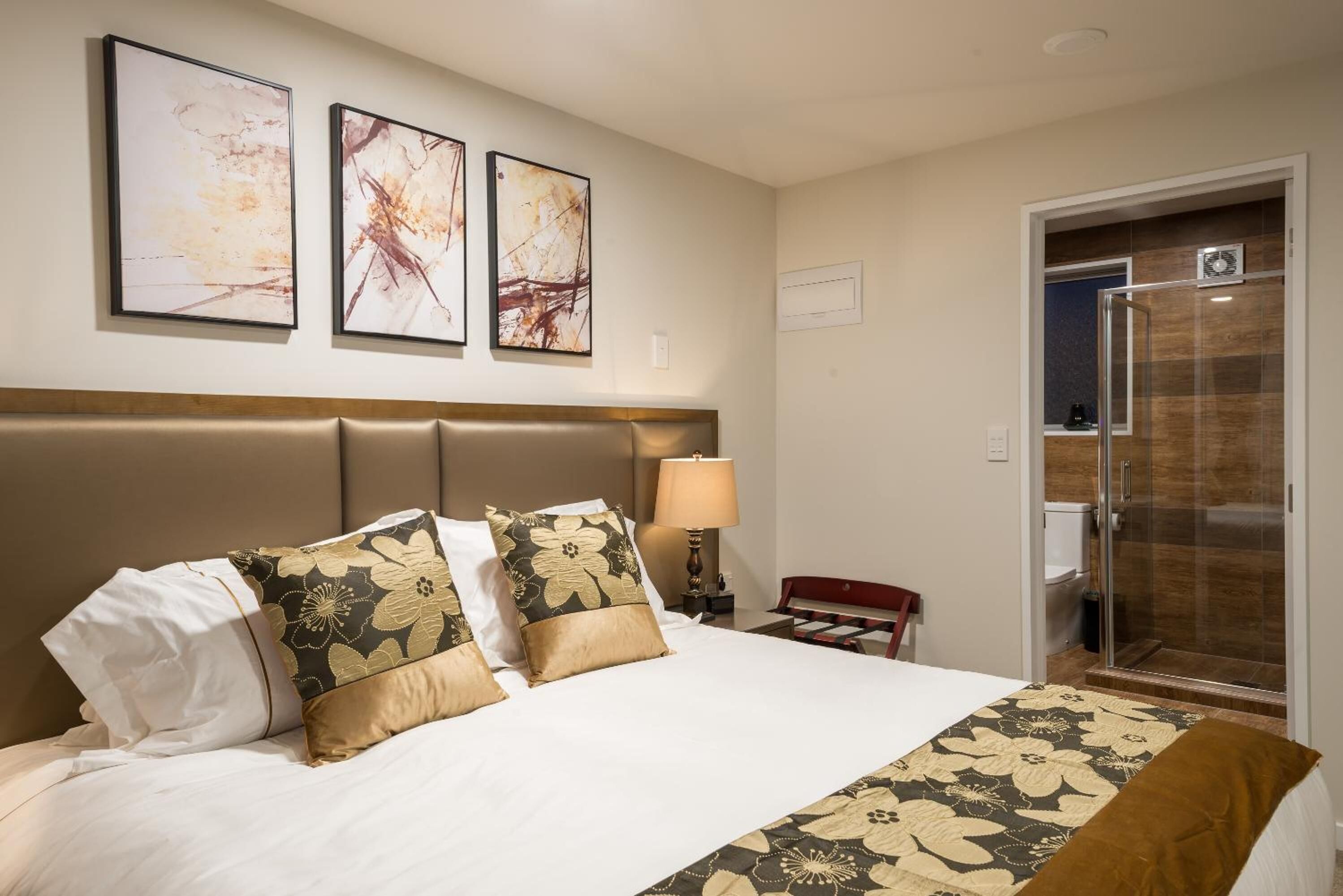 Een hotelkamer met een groot bed, een hoofdeinde, een nachtkastje met een lamp en een douche.