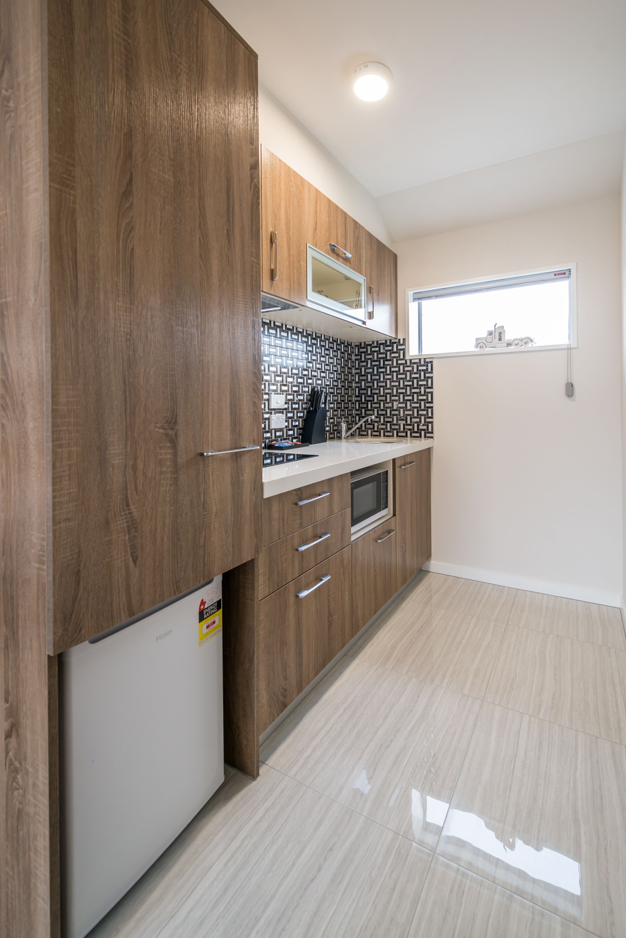 Een moderne keuken met houten kastjes, een wit aanrecht en een betegelde achterwand.