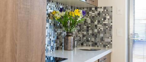 Una cocina moderna con armarios de madera, encimera blanca y salpicadero con diseño de mosaico.