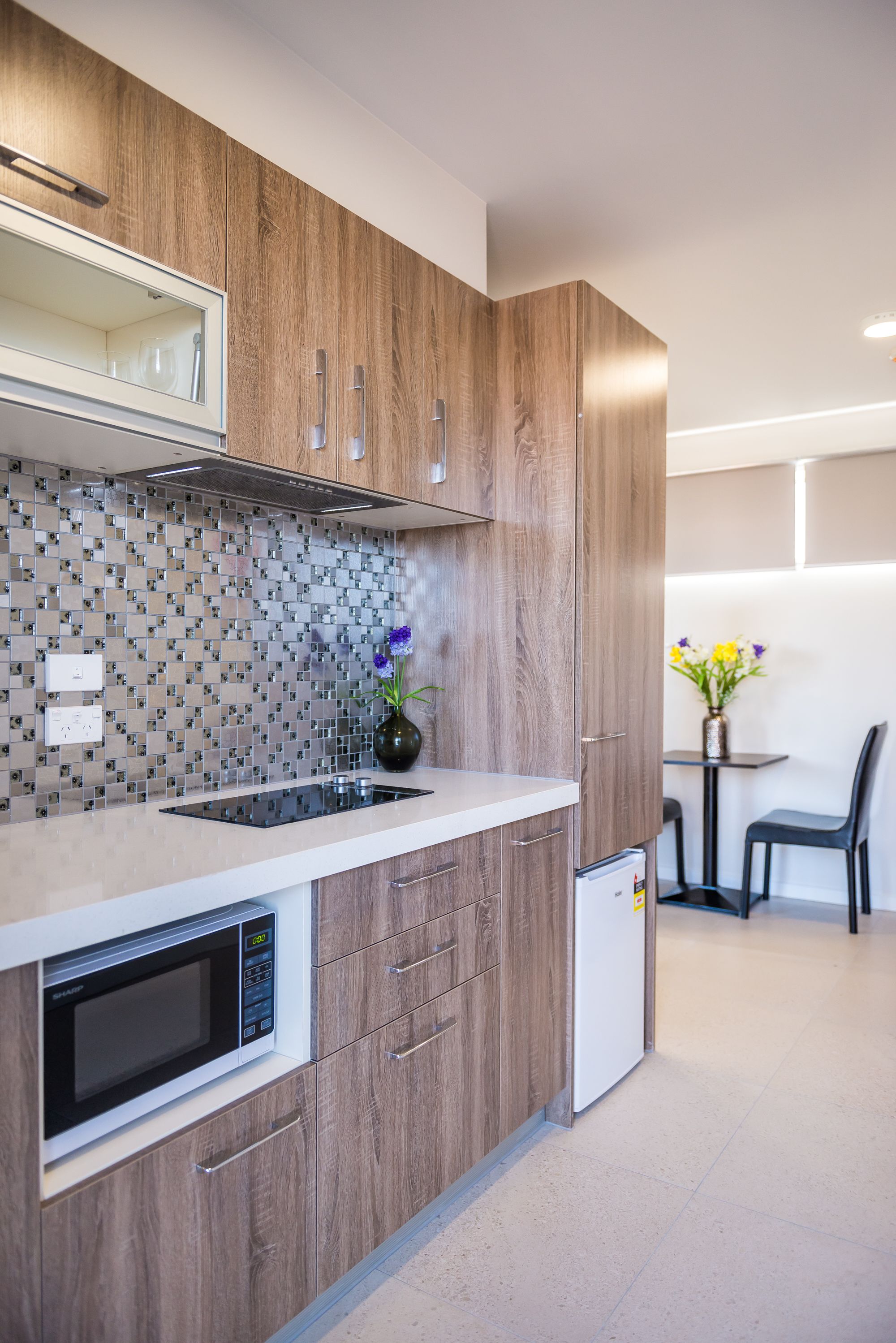 A modern kitchen with wooden cabinets, a built-in microwave, and a tiled backsplash.