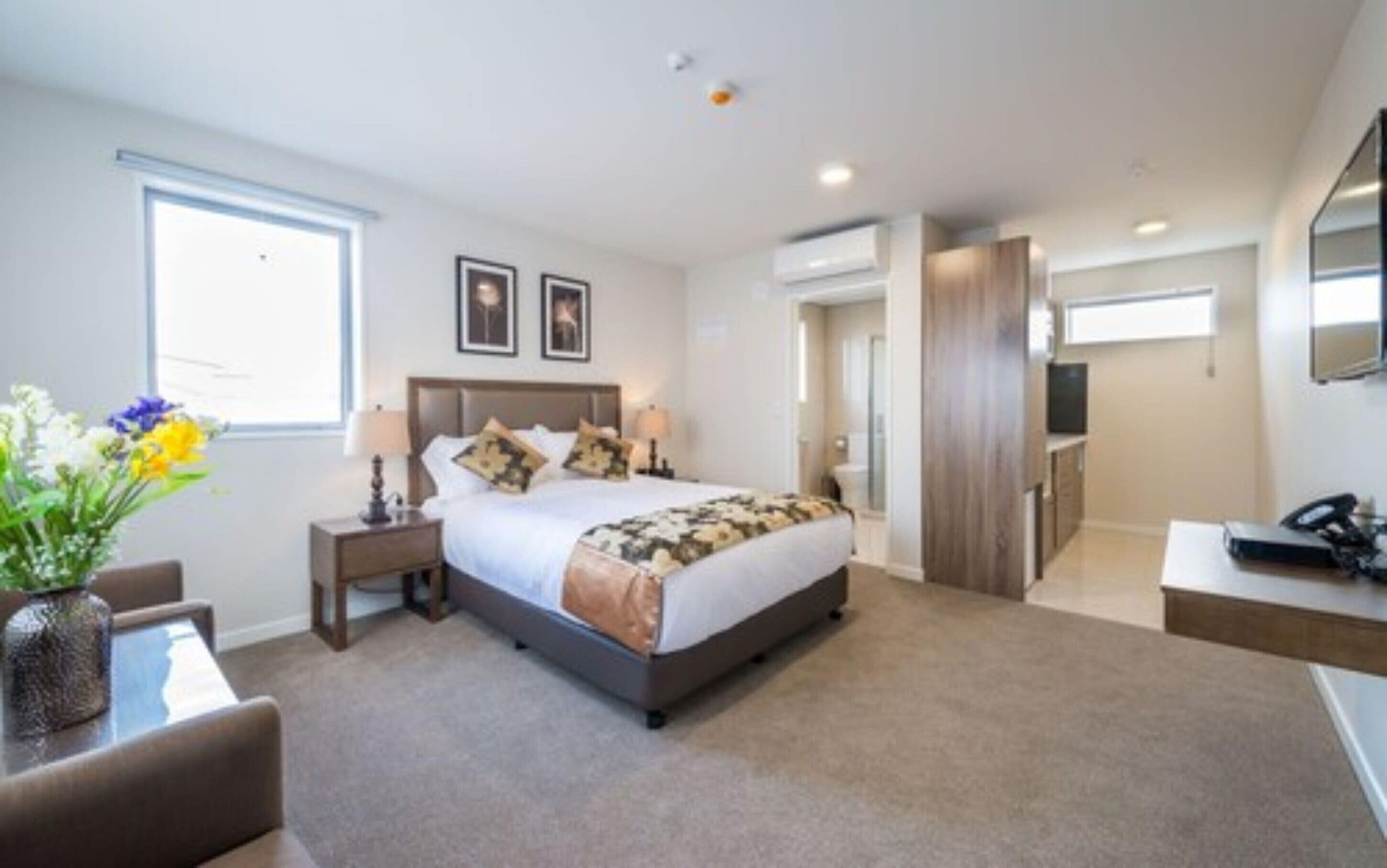 A modern hotel room with a large bed, bedside tables, a desk, and a TV.